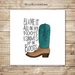 May include: A white background with a brown cowboy boot with a teal shaft and a black graphic. The text "Blame it all on my roots I showed up in boots" is written in black.