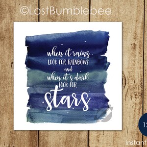 May include: A watercolor print with a blue and gray background. The print features the text "when it rains look for rainbows and when it's dark look for stars".