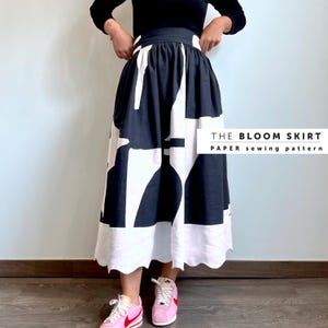 May include: A black and white skirt with a geometric print. The skirt has a high waist and a scalloped hem. The skirt is being worn by a person with pink trainers. The text on the image reads "THE BLOOM SKIRT PAPER sewing pattern".