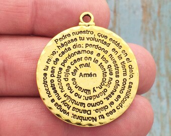 May include: Gold-toned metal pendant with a circular design featuring the Lord's Prayer in Spanish. The text is inscribed in a spiral pattern around the pendant.