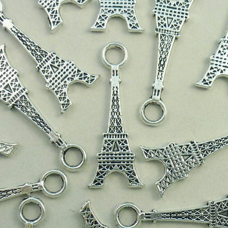 May include: A group of silver Eiffel Tower charms with a loop at the top for attaching to jewelry or other crafts.