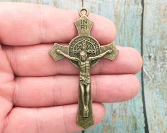 May include: Antique gold-toned metal crucifix pendant with a depiction of Jesus Christ on the cross. The cross features a circular medallion with the inscription "INRI" and the words "ORA PRO NOBIS" around the edge.
