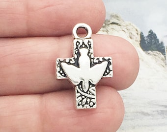 Puede incluir: Encanto de plata con una cruz de diseño adornado y una paloma en el centro.