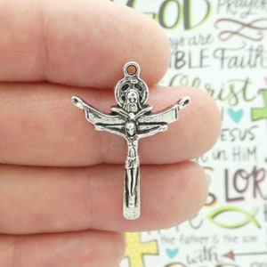 May include: Silver-toned metal charm featuring a crucifix with a detailed depiction of Jesus Christ on the cross. The charm has a loop at the top for attaching to a necklace or bracelet.