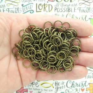 May include: A large pile of antique gold jump rings. The rings are all the same size and are arranged in a random pattern.