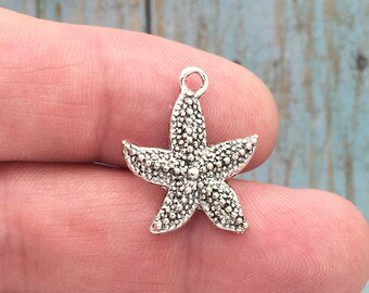 May include: Silver-toned starfish charm with a textured surface. The charm has a loop at the top for attaching to jewelry or other crafts.