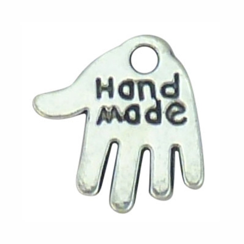 May include: A silver-toned hand-shaped charm with the words "Hand Made" embossed on the palm. The charm has a small hole at the top for attaching to jewellery. The design is simple and elegant, suitable for handmade crafts.