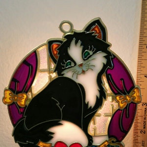 May include: A stained glass nightlight featuring a black and white cat with green eyes and a red heart. The cat is surrounded by a purple and gold background with bows. The nightlight says "I Love Cats" in gold letters.