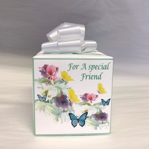 May include: A white gift box with a white satin ribbon tied in a bow. The box is decorated with a watercolor design of flowers and butterflies. The text "For A special Friend" is printed on the front of the box.