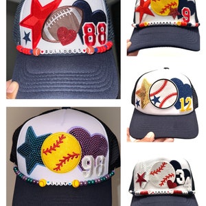 May include: Four different trucker hats with various sports-themed patches and beaded trim. The hats are all white with a navy blue mesh back and a navy blue brim. The patches include a baseball, softball, football, and a star. The beaded trim includes different colors and beads, including red, blue, green, purple, and yellow.