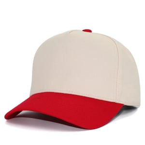 May include: A five-panel baseball cap featuring a solid cream-colored crown and a contrasting bright red curved brim. The cap includes a small red button at the top center where the panels meet, providing a clean and structured appearance.