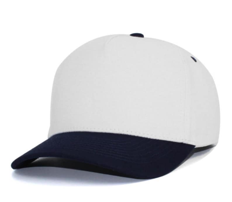 May include: A five-panel baseball cap featuring a solid white crown and a contrasting dark navy blue curved brim. The cap includes a small dark navy blue button at the top center and matching dark navy blue eyelets on the side panels for ventilation.