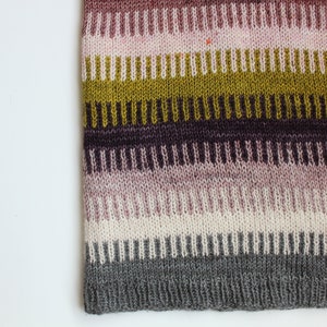 May include: Striped knitted fabric in shades of pink, purple, green, and gray. The fabric has a textured, ribbed pattern.