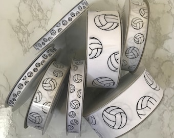 May include: White satin ribbon with a black volleyball print. The ribbon is rolled up and stacked on a white surface.