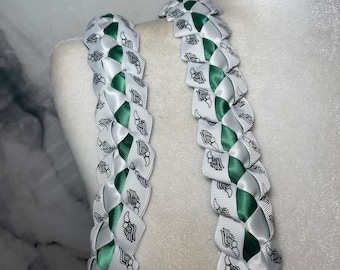 May include: Two white and green braided leis with a black and white wing design.