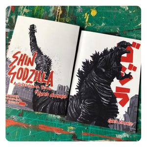 May include: A sketchbook tribute to Shin Godzilla, a Japanese monster movie. The cover features a black and white illustration of Godzilla with the title "Shin Godzilla: A Sketchbook Tribute by Chris Cowdril" in red and white text.