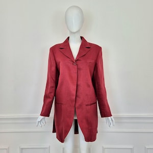 Può includere: Un blazer lungo color borgogna con una chiusura a bottone singolo e due tasche. Il blazer ha un orlo posteriore leggermente più lungo del davanti.