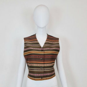 Può includere: Un gilet a righe marroni, arancioni e beige con scollo a V e chiusura con bottoni.