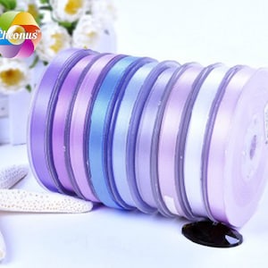 May include: A roll of purple, lavender, and blue satin ribbon. The ribbon is wound around a spool and is ready to be used for crafting or decorating.