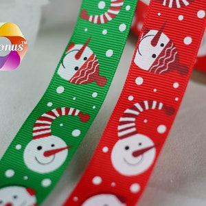 Pode incluir: Dois rolos de fita de Natal com um padrão de boneco de neve. Um rolo é vermelho com bonecos de neve brancos e o outro é verde com bonecos de neve brancos.