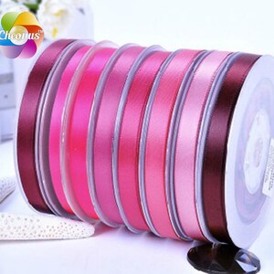May include: A spool of pink, purple, and burgundy satin ribbon. The ribbon is wound around a clear plastic spool with a white label.