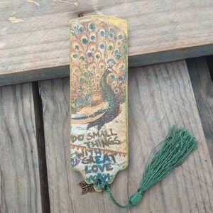 May include: A yellow and green peacock bookmark with a tassel. The bookmark has the text "Do small things with great love" on it.