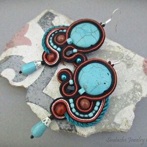 May include: A pair of turquoise and orange earrings with a silver hook closure. The earrings are made with a variety of materials, including beads, wire, and fabric. The earrings are a unique and stylish accessory.