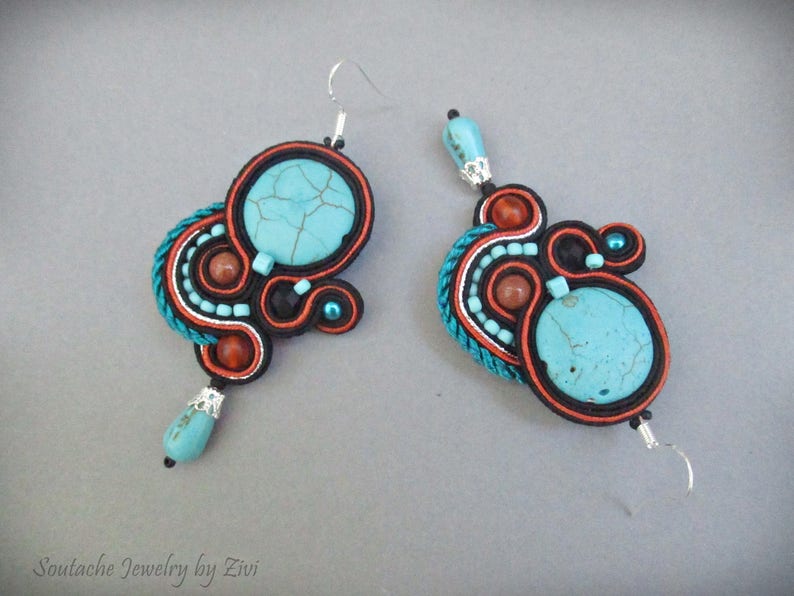 May include: A pair of turquoise and orange earrings with intricate beaded designs. The earrings feature a large turquoise stone in the center of each earring.