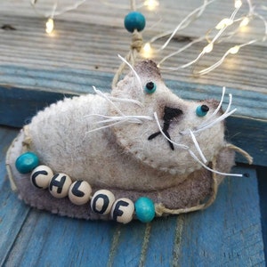 May include: A gray felt cat ornament with turquoise beads spelling out the name "Chloe".