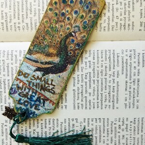May include: A green and gold peacock bookmark with a green tassel. The bookmark has the text "Do small things with great love" printed on it.