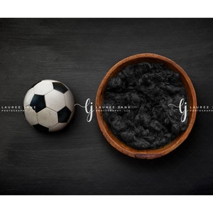 May include: A black and white soccer ball and a wooden bowl filled with black faux fur on a black background. The text "Lauree Jane Photography, LLC" is written on the left and right sides of the image.