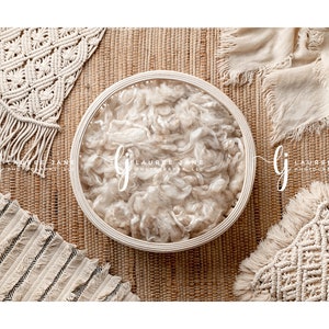 Puede incluir: Una cesta tejida blanca llena de material blanco y esponjoso, rodeada de artículos de crochet beige y blanco sobre un fondo marrón tejido.