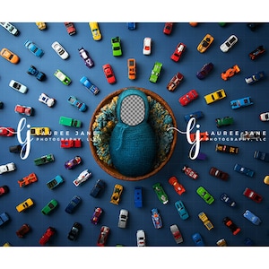 May include: A newborn photography prop featuring a blue knitted cocoon nestled in a wooden bowl, surrounded by a multitude of colorful toy cars on a blue grid background. The image includes the text "LAUREE JANE PHOTOGRAPHY, LLC".