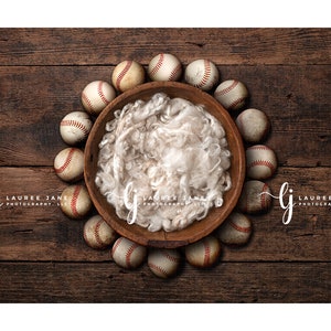 以下が含まれることがあります： 茶色の木製の背景に、白いフェイクファーで満たされた木製のボウルが、野球ボールの輪で囲まれています。画像の左と右に「LAUREE JANE PHOTOGRAPHY, LLC」のテキストが表示されています。