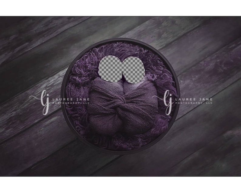 May include: A purple fabric backdrop with a round, dark gray bowl in the center. The bowl is filled with a purple fabric swaddle and two white circles.