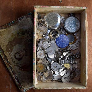 Vecchia scatola di sigari piena di custodie per parti di orologi meccanici sovietici d'epoca per progetti artistici Steampunk