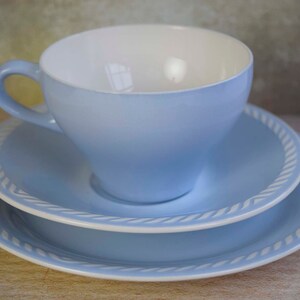 May include: A light blue teacup and saucer set with a white rope design around the edge.