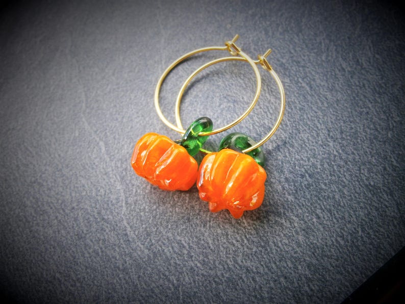 May include: Gold hoop earrings with orange and green glass pumpkin charms.