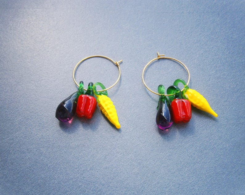 Vergoldete Creolen mit Gemüseanhängern (Aubergine, Paprika und Maiskolben) aus Lampwork Glas. Die Creolen sind aus vergoldetem Edelstahl. Die Aubergine ist violett, die Paprika rot und der Maiskolben gelb. Alle Anhänger haben einen grünen Stängel