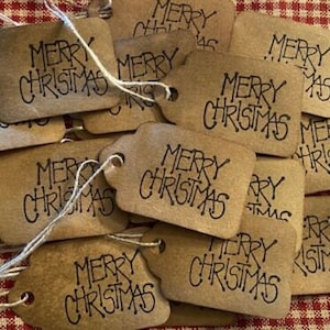 May include: A collection of brown paper gift tags with the text "Merry Christmas" written in black ink. The tags are tied with twine and are ready to be used for gift wrapping.