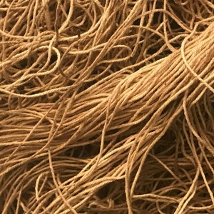 May include: Close-up of a tangled pile of natural-colored twine. The twine appears to be made of a fibrous material, with a slightly rough texture. The image is well-lit, highlighting the details of the individual strands and the overall texture of the twine.