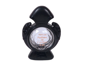 Puede incluir: Un frasco de perfume Panthère de Cartier de vidrio negro con una etiqueta dorada. El frasco tiene forma de pantera y un tapón de vidrio transparente. La etiqueta dice "Parfum Panthere de Cartier 4 ml".