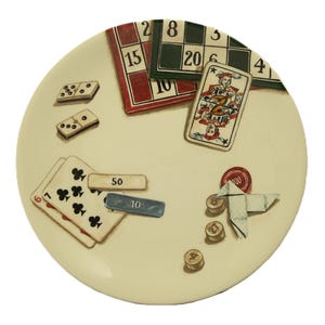K&ouml;nnte beinhalten: Ein cremefarbener dekorativer Teller mit Illustrationen von Spielkarten, Dominosteinen und Spielbrettern. Der Teller enth&auml;lt eine Spielkarte mit einem Narren, Bingokarten und Pokerchips. Das Design hat eine Vintage-&Auml;sthetik, handgemalt.