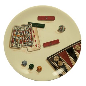 K&ouml;nnte beinhalten: Ein cremefarbener Teller mit einem spielthemenbezogenen Design. Der Teller enth&auml;lt Spielkarten, W&uuml;rfel, rote und gr&uuml;ne rechteckige Marker, eine Murmel und ein Backgammon-Brett. Die Spielkarten zeigen detaillierte Illustrationen und die W&uuml;rfel sind blau, gr&uuml;n und orange.