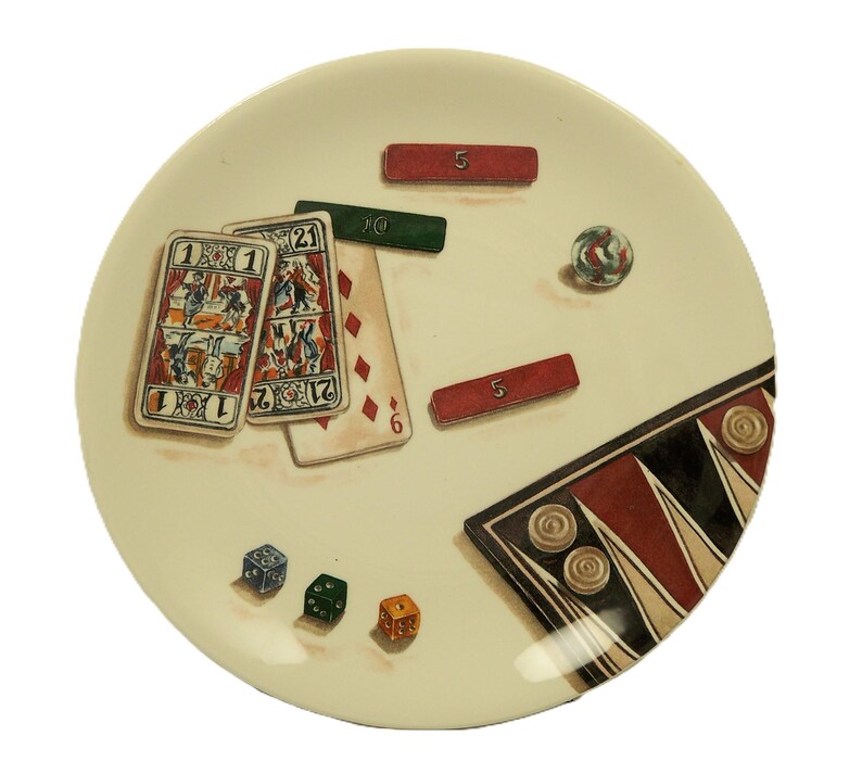 K&ouml;nnte beinhalten: Ein cremefarbener Teller mit einem spielthemenbezogenen Design. Der Teller enth&auml;lt Spielkarten, W&uuml;rfel, rote und gr&uuml;ne rechteckige Marker, eine Murmel und ein Backgammon-Brett. Die Spielkarten zeigen detaillierte Illustrationen und die W&uuml;rfel sind blau, gr&uuml;n und orange.