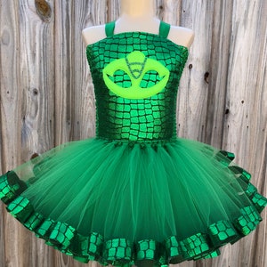 May include: Green tulle tutu with a green and silver bodice featuring a green and silver emblem. The bodice has a crocodile skin pattern.