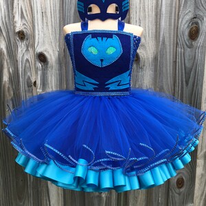 May include: A blue tulle tutu with a blue and black felt cat costume top and a matching cat mask. The tutu has a blue satin ribbon trim.