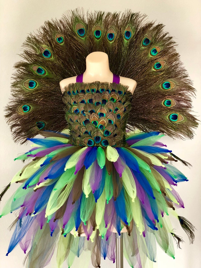May include: A peacock costume for girls, featuring a tutu skirt with green, blue, and purple tulle, a peacock feather bodice, and a large peacock feather tail.