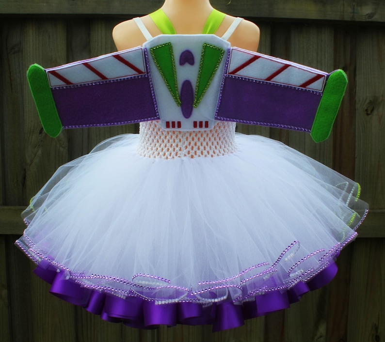 May include: White tulle tutu with purple satin ribbon trim and a purple felt Buzz Lightyear costume wing with green and white accents.