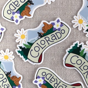 Several illustrated Colorado vinyl stickers scattered on a neutral background.